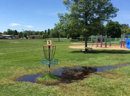 The #5 basket at the Polaris Park disc golf course sits in a puddle of water after a recent rain.