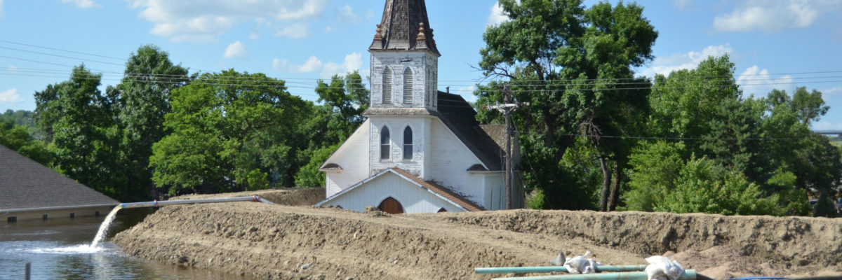 Minot's original Augustana Lutheran Church sits just behind temporary flood levees in 2011 at its location near Broadway and 4th Ave. NW. The church was later demolished. Image courtesy of FEMA.